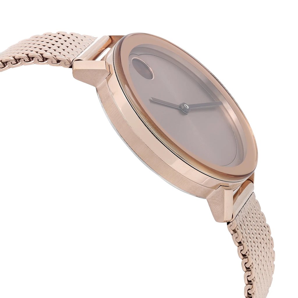 An image of a wristwatch shown from the side profile view, opposite the crown. The watch features a sleek, rose gold case and a matching mesh strap. The angle highlights the round face and minimalist design. The watch is positioned at a slight upward angle, showcasing its new condition with defects.