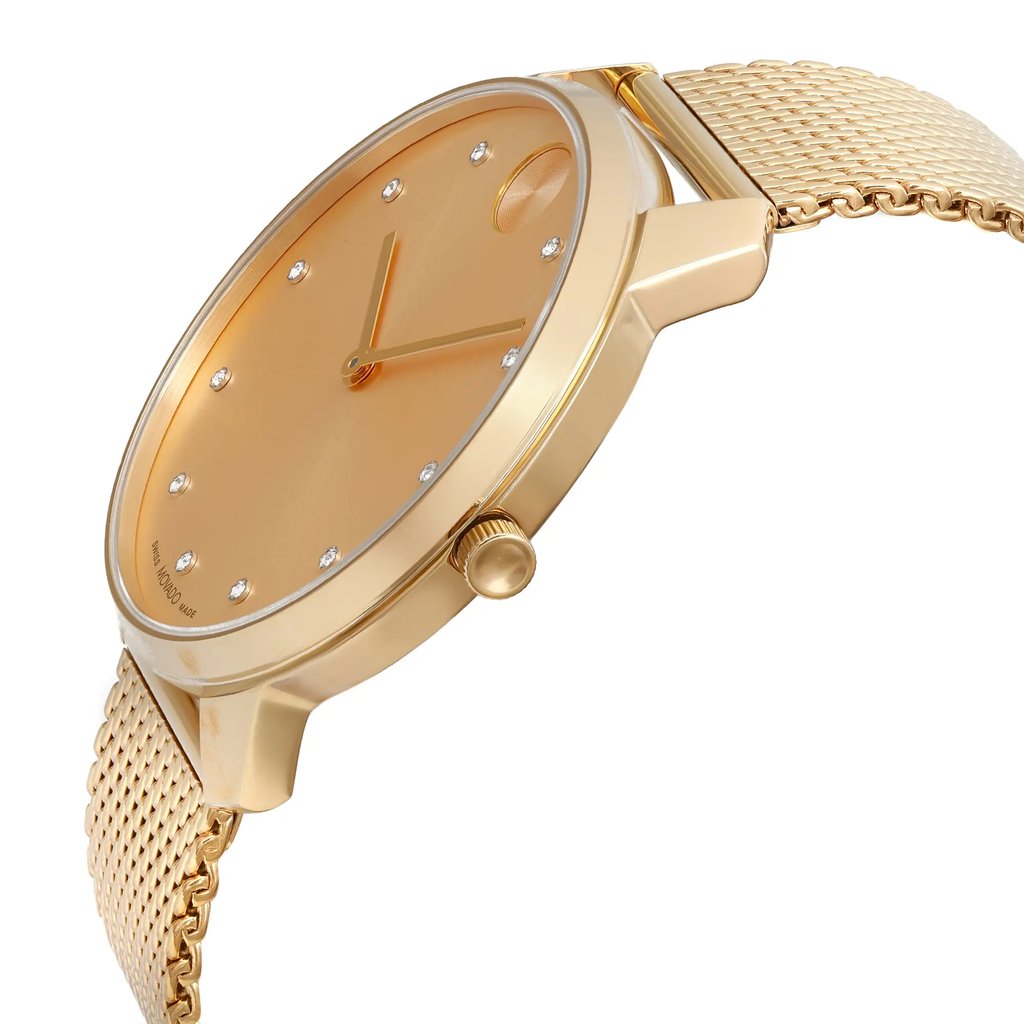 An image of a pre-owned wristwatch shown from a side profile view, highlighting the crown. The watch features a gold-toned case and a matching mesh band. The face of the watch is angled slightly upward, displaying minimalist hour markers and hands. The photograph is taken at a close distance, emphasizing the sleek design and details of the watch.