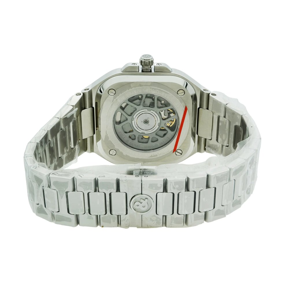 An image of a Bell & Ross men's wristwatch viewed from the back, showing the exhibition caseback. The stainless steel cushion-shaped case and band are in focus, with the watch positioned slightly to the left and angled to show the clasp mechanism. The watch appears as a display model, with a visible automatic movement through the case back, and is photographed at a close distance against a white background. The watch was never worn.