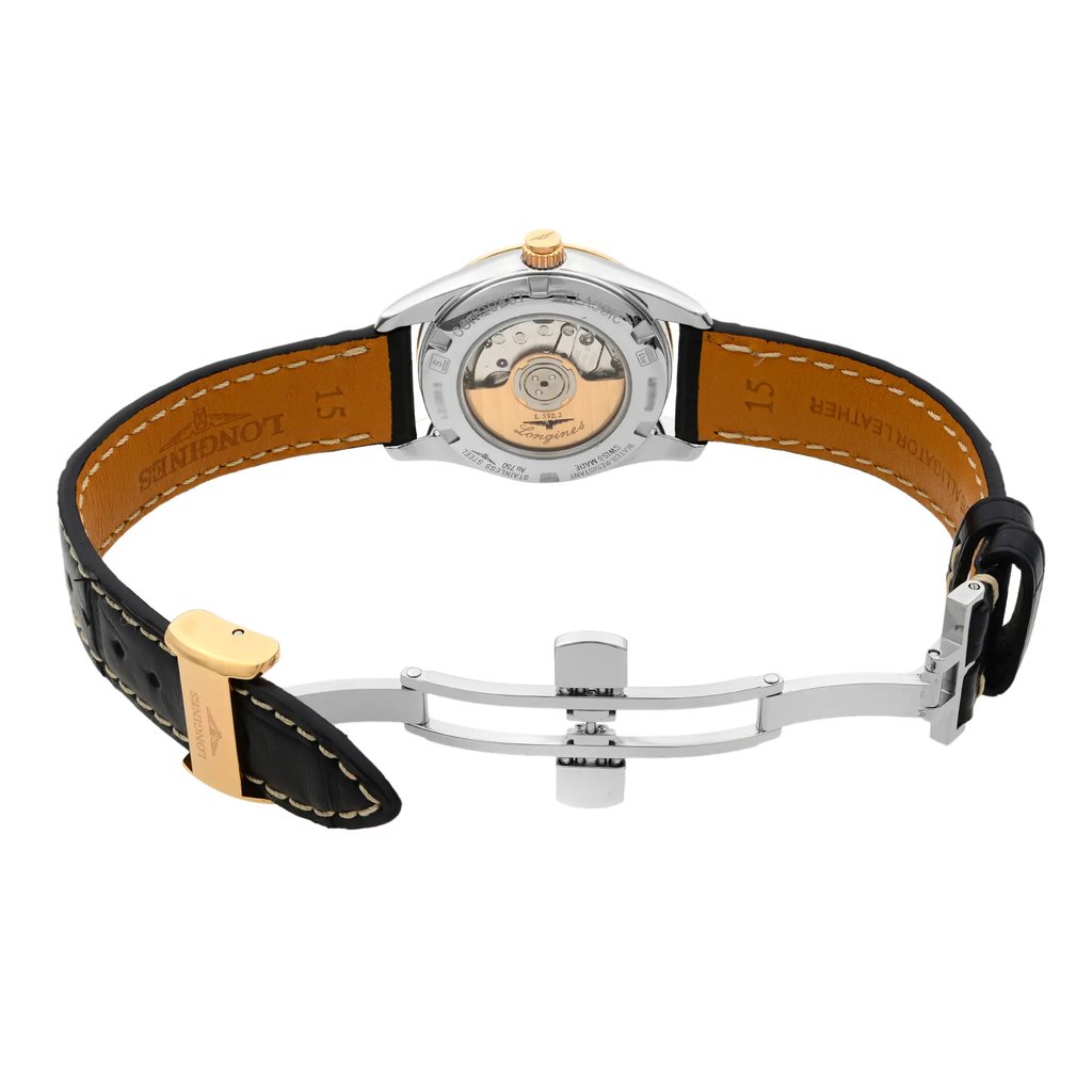 An image of a wristwatch displayed from the back view with an open clasp. The watch is positioned horizontally, showing the internal mechanism through a transparent case back. The angle is slightly elevated, providing a clear view of the leather strap's interior, which is brown with visible stitching and markings. The distance is close, focusing on the details of the watch's back and clasp.