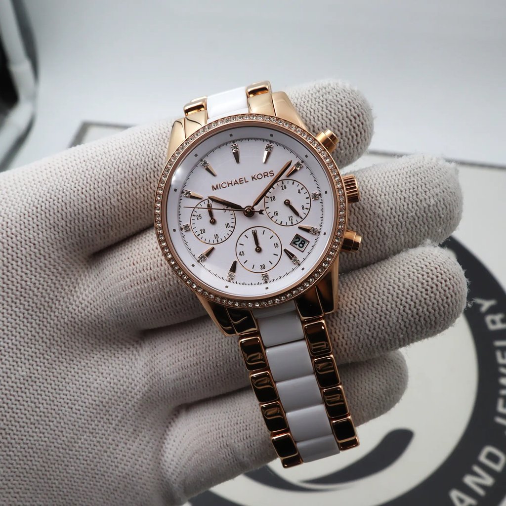 An image of a Wristwatch by Michael Kors. This Display Model item is designed for Women, featuring a Dress/Formal style. It has a Quartz movement and an Analog display with a White dial color. The indices include 12-Hour Dial,Stick Indexes. The band is made of Stainless Steel,Acetate and the case is made of Stainless Steel. The watch has a Round shape with a case size of 37 mm and a case thickness of 11.5 mm.