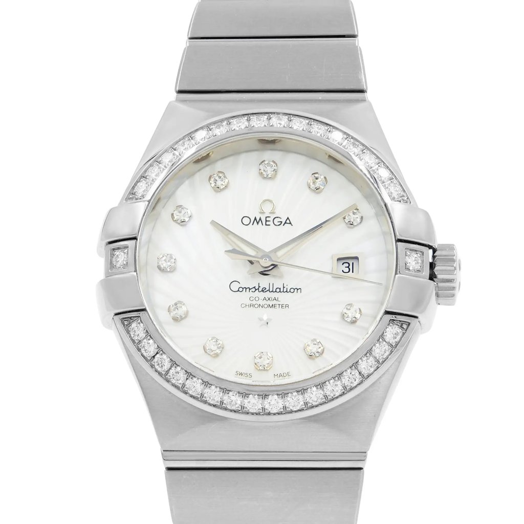 An image of a women's OMEGA wristwatch, viewed from a straight-on angle at a close distance. The watch features a silver bracelet and a round face with diamond hour markers. The bezel is encrusted with small diamonds, and the date is displayed at the 3 o'clock position. The watch face is white with the brand name "OMEGA" and "Constellation" inscribed on it.