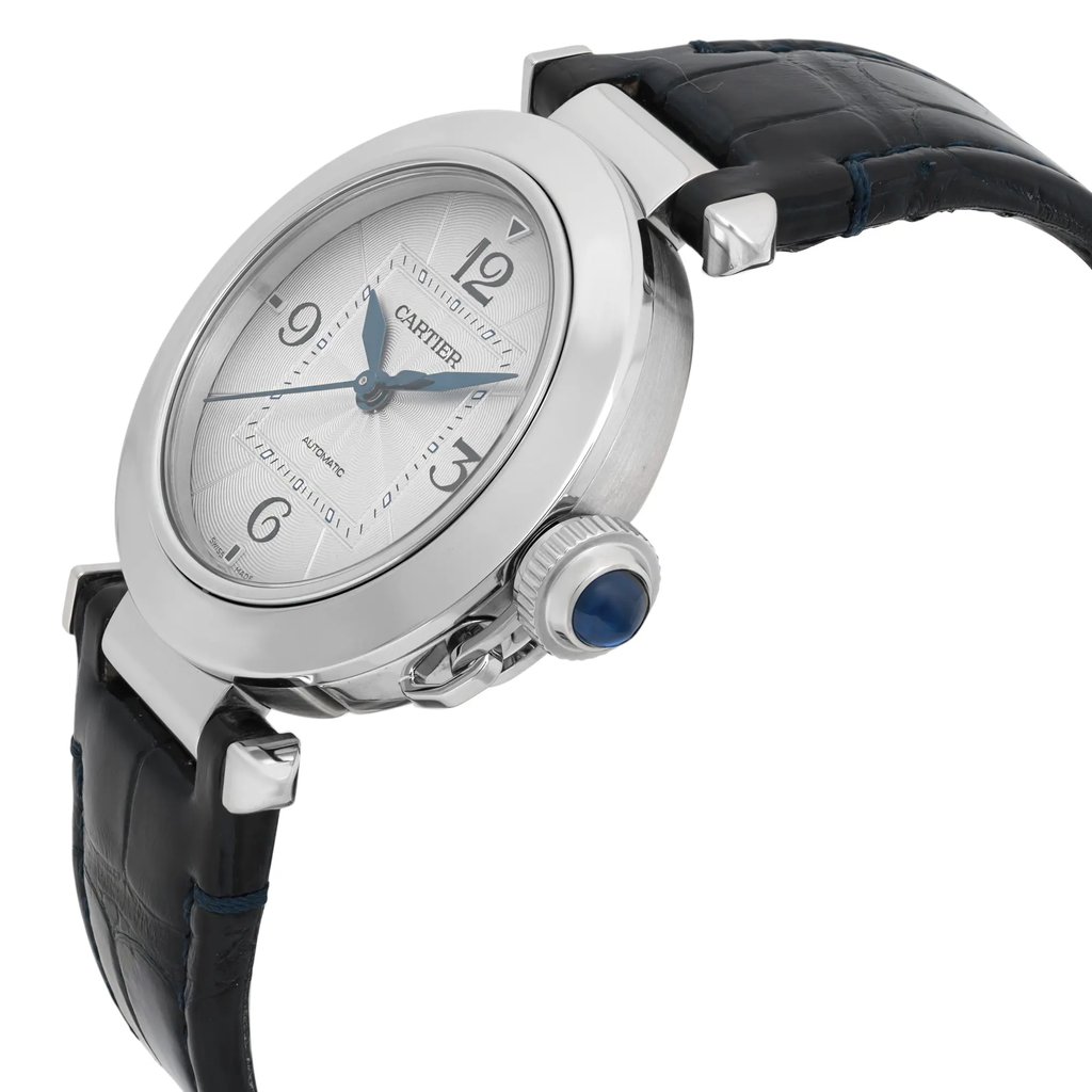An image of a pre-owned men's Cartier wristwatch displayed at a three-quarter angle from the front right side. The watch features a round silver dial with blue hands and Arabic numerals at the 3, 6, 9, and 12 o'clock positions. The case is stainless steel, and the crown is adorned with a blue cabochon. The watch is paired with a black leather strap, visible from a close distance with a slight upward angle emphasizing its elegant design.