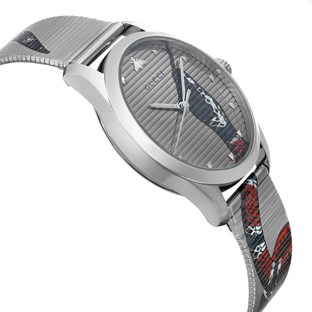 An image of an unworn Gucci wristwatch for unisex adults, showcasing a side profile view from the side opposite the crown. The watch features a round stainless steel case with a casual style, and a silver dial adorned with an animal print pattern. The stainless steel band displays a portion of the same animal print, visible on the lower half of the band. The watch is captured from a close distance, emphasizing the dial and the side contour of the watch.