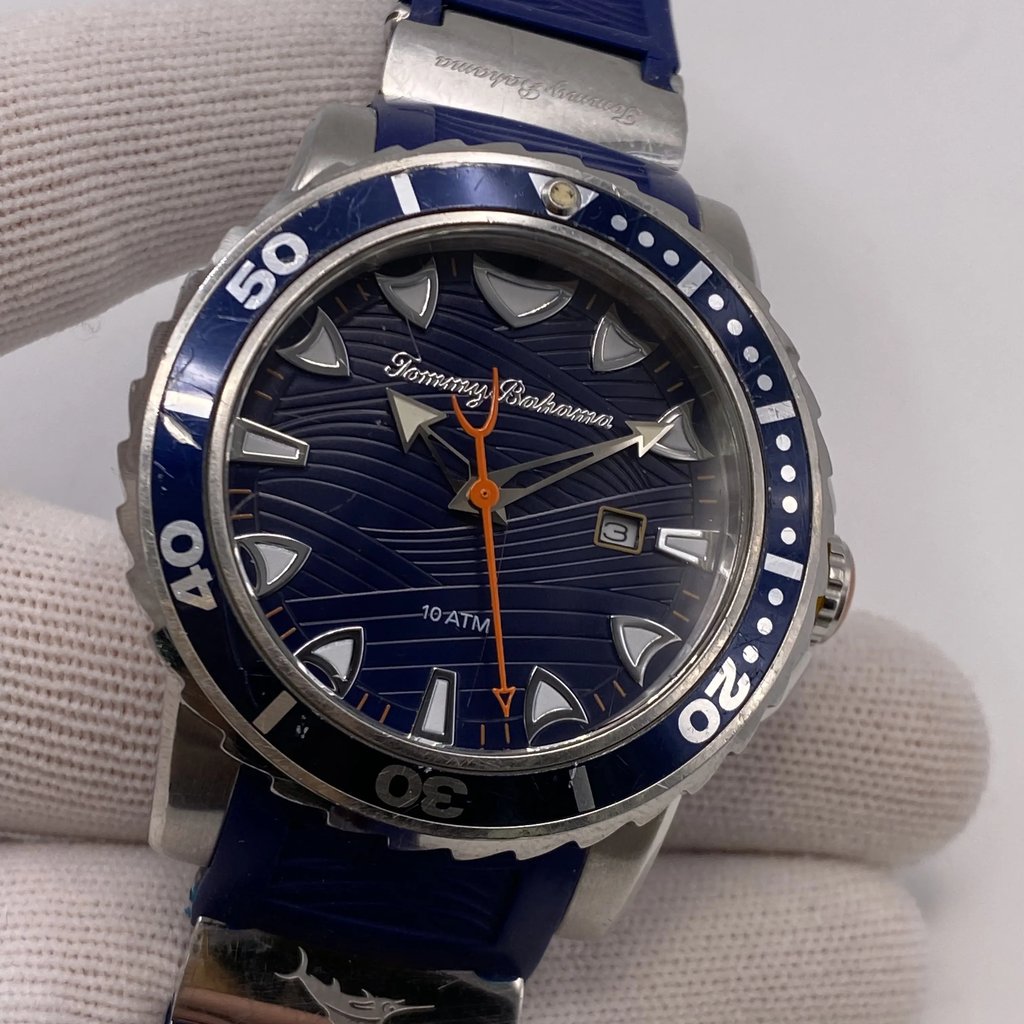 An image of a Wristwatch by Tommy Bahama. This Pre Owned item is designed for Men, featuring a Diver style. It has a Quartz movement and an Analog display with a Blue dial color. The indices include 12-Hour Dial,Non-Numeric Hour Marks. The band is made of Rubber and the case is made of Stainless Steel. The watch has a Round shape with a case size of 44 mm and a case thickness of 14 mm.
