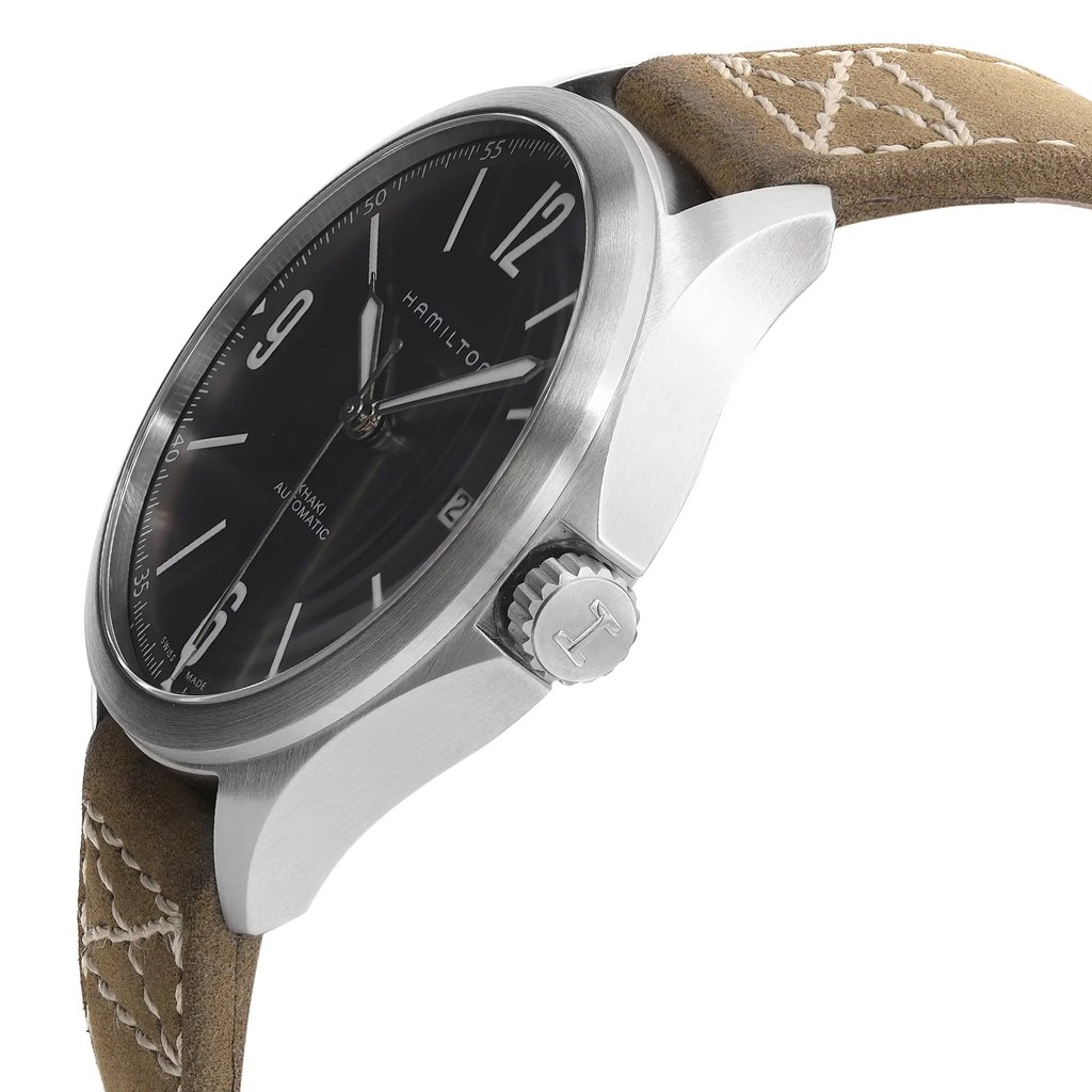 An image of a wristwatch taken from a side profile view, displaying the crown prominently. The watch face is angled slightly upward, showcasing a black dial with clear numerals. The watch is in display model condition, and the crown features a textured edge. The beige leather strap is visible, detailed with white stitching. The image is captured at a close distance to highlight the design features.