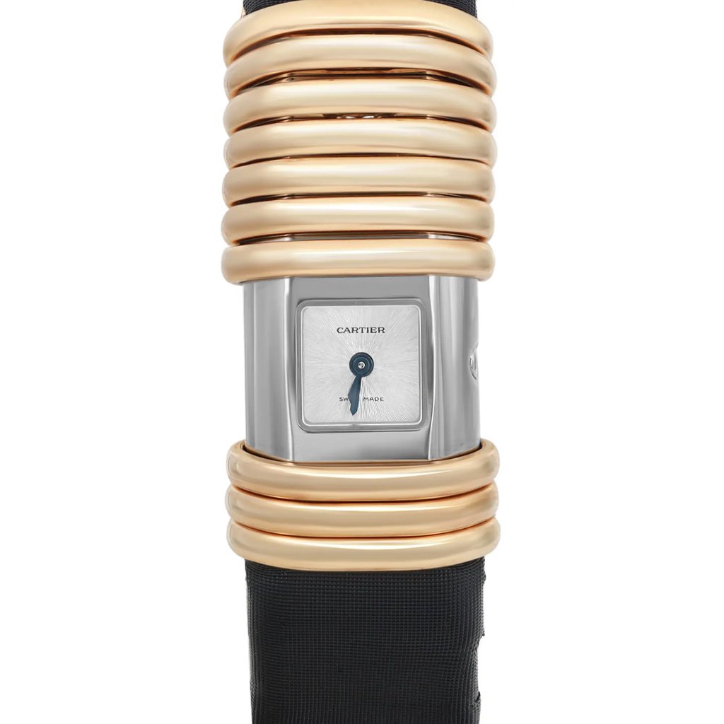 An image of a pre-owned wristwatch, shown in a front close-up shot of the watch face. The watch has a rectangular dial with a metallic finish and minimalistic design. The bezel is adorned with several polished gold rings, and the strap is dark in color. The brand name is visible on the watch face.