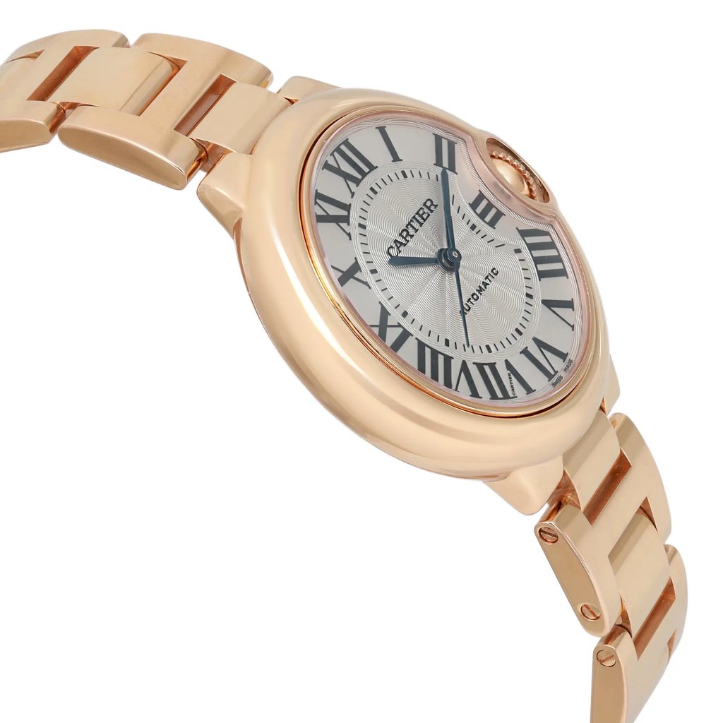 An image of a pre-owned wristwatch in a side profile view, opposite of the crown. The watch is positioned at a slight angle, showcasing its sleek, metallic bracelet and elegantly curved case. The distance is close enough to clearly display the watch face, which features Roman numerals and blue hands. The overall design appears sophisticated and luxurious.