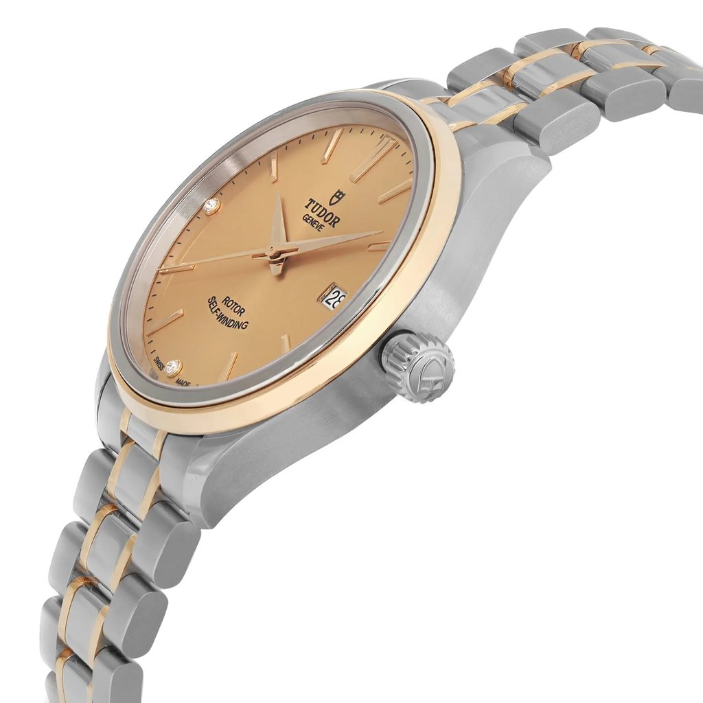 An image of a wristwatch displayed in a side profile view, highlighting the crown. The watch features a two-tone metal band and a gold-toned dial. The angle emphasizes the sleek design and unworn condition of the watch, showcasing its polished finish. The distance is close enough to clearly see the details on the dial and crown.