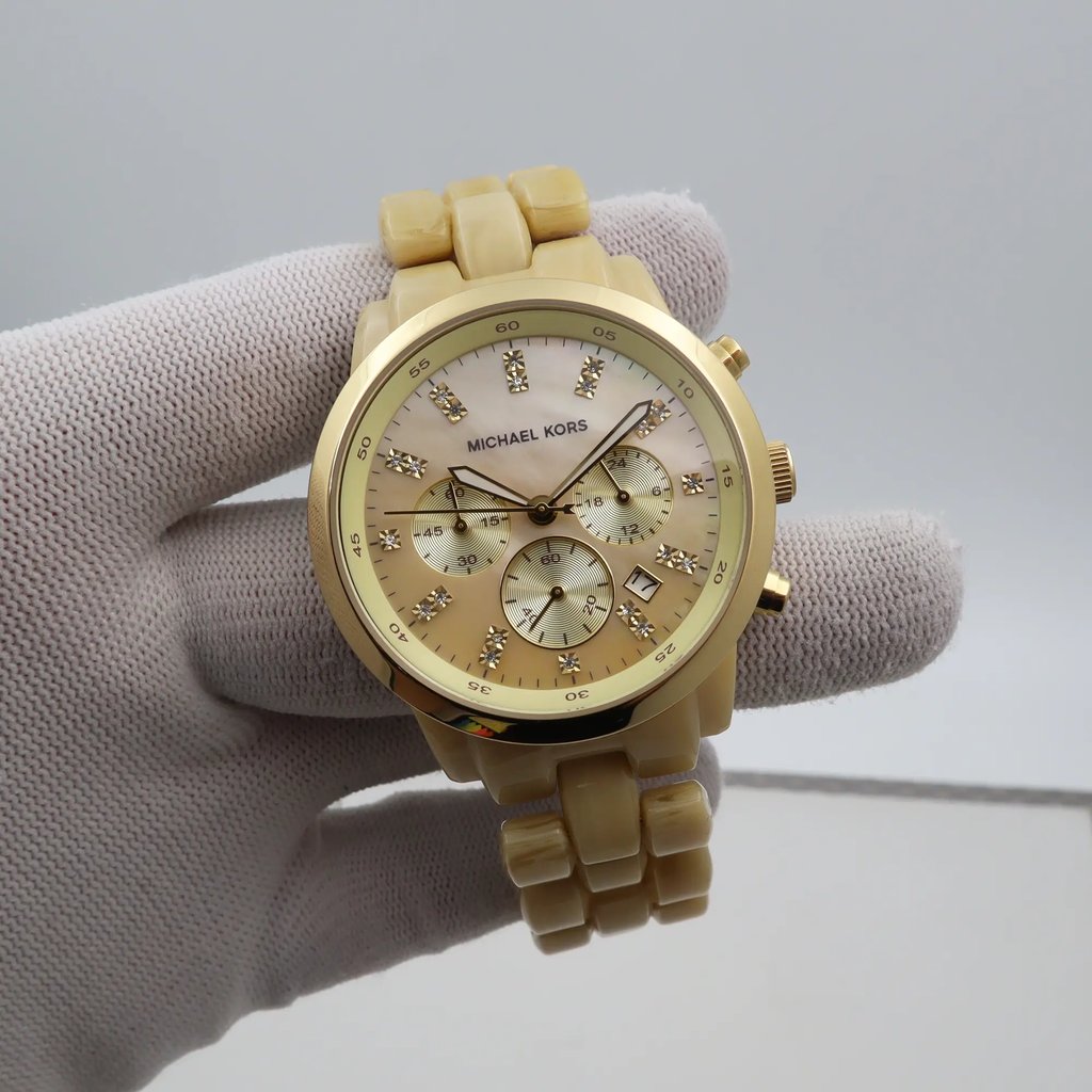 An image of a Wristwatch by Michael Kors. This New With Defects item is designed for Men, featuring a Casual style. It has a Quartz movement and an Analog display with a Champange Mother of Pearl dial color. The indices include 12-Hour Dial,Stick Indexes. The band is made of Plastic and the case is made of Stainless Steel. The watch has a Round shape with a case size of 43 mm and a case thickness of 13 mm.