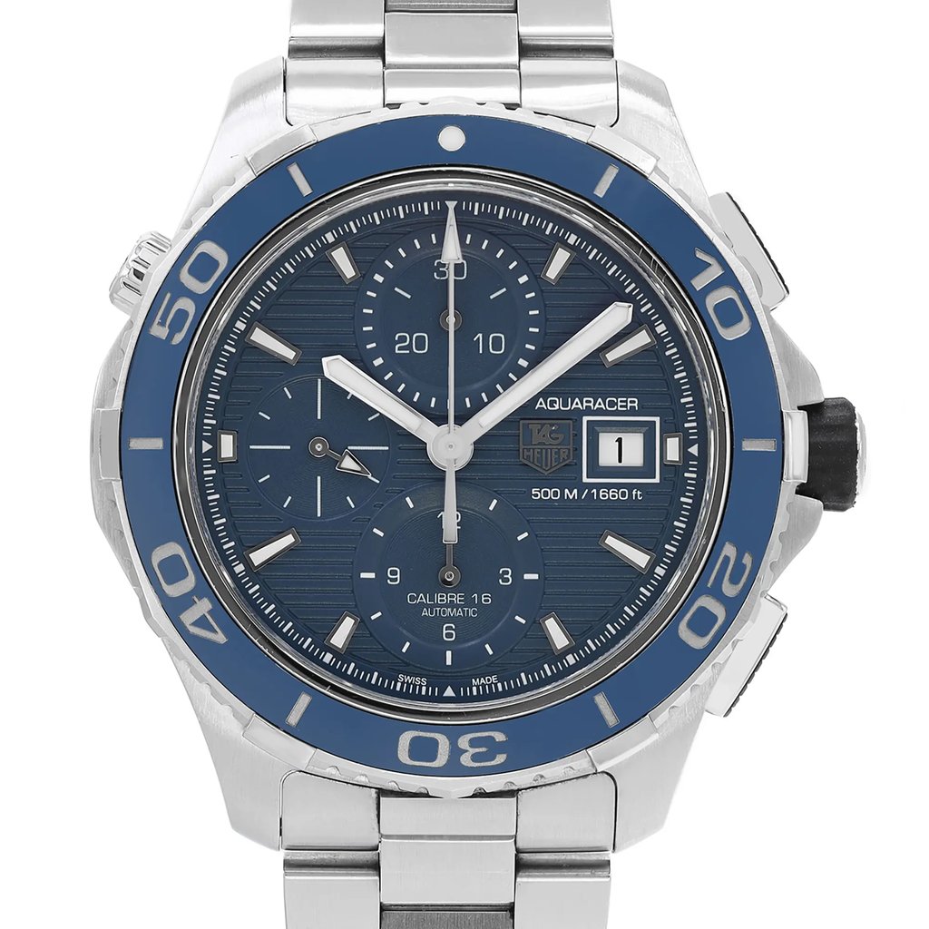 An image of a pre-owned TAG Heuer men’s diver wristwatch, captured from a front close-up angle focusing on the watch face. The round dial is blue, matching the blue bezel. It features stick indexes, a 12-hour dial with non-numeric hour marks, a chronograph, and a date indicator. The watch has luminous hands. The stainless steel band and case are also visible. The condition is classified as good.