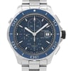 An image of a pre-owned TAG Heuer men’s diver wristwatch, captured from a front close-up angle focusing on the watch face. The round dial is blue, matching the blue bezel. It features stick indexes, a 12-hour dial with non-numeric hour marks, a chronograph, and a date indicator. The watch has luminous hands. The stainless steel band and case are also visible. The condition is classified as good.