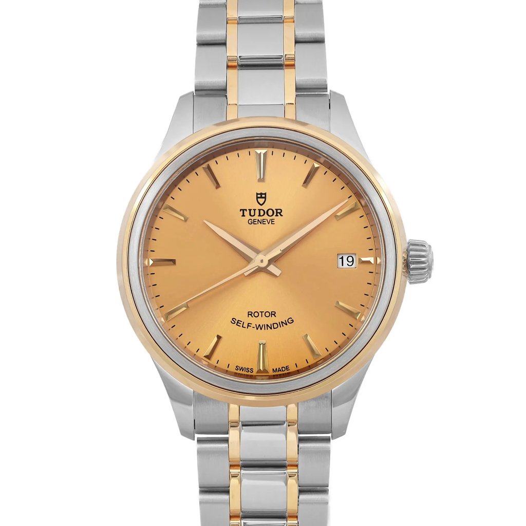 An image of a wristwatch showcasing a front close-up view of the watch face. The watch features a gold-colored dial with silver and gold-tone hour markers and hands. The date is displayed on the right side. The bezel is gold-toned, and the bracelet has a combination of stainless steel and gold links. The watch is in unworn condition.