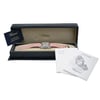 An image of a pre-owned wristwatch positioned inside an open watch box. The watch features a pink strap and is centered within the box, which is displayed from a slightly elevated angle. The box is navy blue with a beige interior, and the brand name is visible inside the lid. To the right of the box, there are two documents partially overlapping, one labeled "World" and the other "Happy Sport." A customer service and warranty certificate card is positioned leaning against the open lid on the left side. The shot is taken at a medium distance, capturing the full view of the box, watch, and accompanying documents.