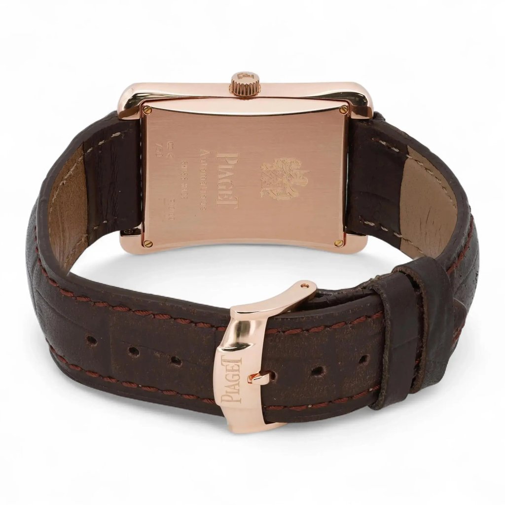 An image of a pre-owned Piaget men's wristwatch, viewed from the back. The watch is positioned upright, showcasing its rectangular rose gold case back with engraved details. The brown leather strap is visible, with a focus on the rose gold clasp, which is partially open. The angle is slightly elevated, capturing the watch at a medium distance, highlighting the craftsmanship and materials.