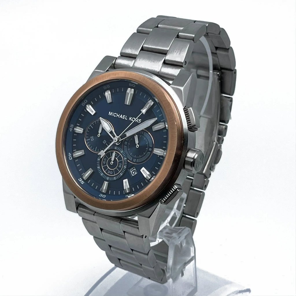 An image of a Wristwatch by Michael Kors. This New With Defects item is designed for Men, featuring a Dress/Formal style. It has a Quartz movement and an Analog display with a Blue dial color. The indices include 12-Hour Dial,Non-Numeric Hour Marks,Stick Indexes. The band is made of Stainless Steel and the case is made of Stainless Steel. The watch has a Round shape with a case size of 47 mm and a case thickness of 12 mm.