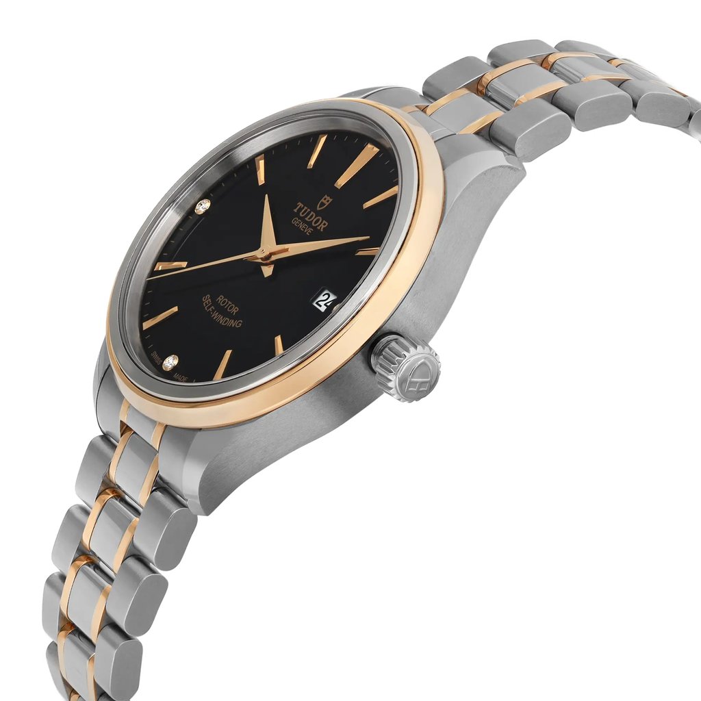 An image of a wristwatch in unworn condition, viewed from a side profile angle. The crown is prominently displayed on the right side. The watch features a two-tone design with a sleek black dial, gold markers, and a date window. The bracelet combines silver and gold links, adding to the elegant appearance.