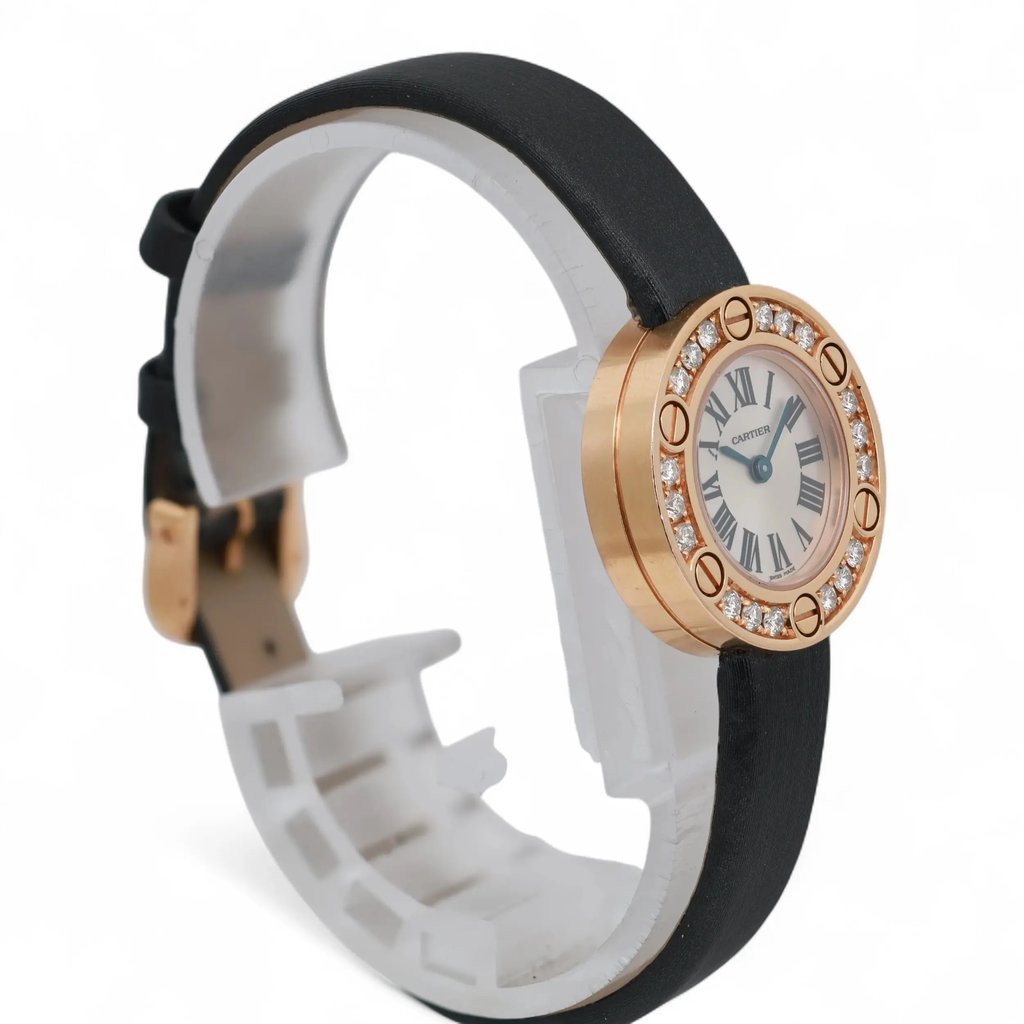 An image of a pre-owned Cartier women's wristwatch. The watch is positioned at an angle, showcasing the round face with Roman numeral markings and a rose gold bezel adorned with diamonds. The black leather strap is partially visible, and the watch is displayed on a white stand, viewed from a close distance.