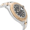 An image of a pre-owned wristwatch shown from a side profile view, opposite the crown. The angle highlights the watch's two-tone metal bracelet and the smooth, rounded bezel. The watch face, partially visible, is angled slightly upwards, showcasing the intricate details of the dial and hands. The photograph is taken from a close distance, emphasizing the watch's luxurious design and craftsmanship.