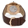 An image of a pre-owned Cartier unisex adult wristwatch. The watch is positioned at a slight angle, showcasing the back view. The case is rose gold with visible engravings, and a clear display reveals the intricate internal mechanisms. The watch is fitted with a dark brown leather strap, and the gold buckle is prominently displayed in the foreground. The photograph is taken from a close distance, highlighting the details of the watch's craftsmanship.
