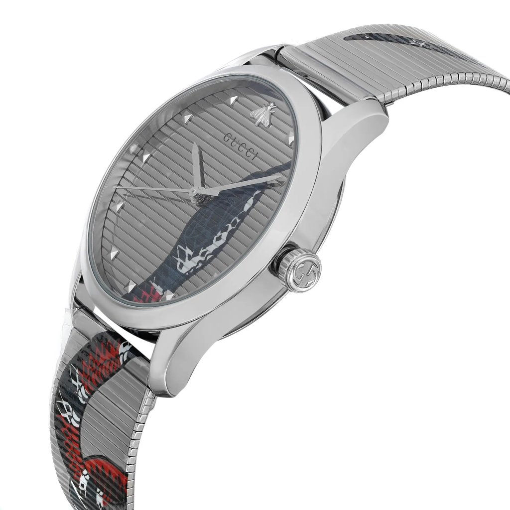 An image of a new, unworn Gucci wristwatch for unisex adults showcased from a side profile view with the crown visible. The watch, captured at a close distance, features a round stainless steel case and a stainless steel band with a distinctive animal print pattern on the silver dial. The brand's logo is subtly displayed at the center top of the dial. The photo angle presents the watch in a way that highlights the watch's shape and design details, including the texture of the band and the sleekness of the case.