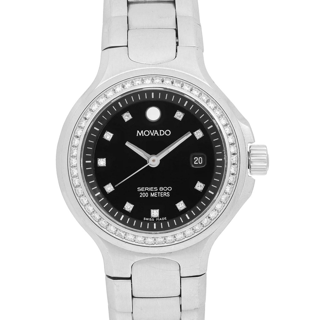 An image of a pre-owned wristwatch shown in a front close-up shot. The watch face is centered, displaying a black dial with silver hands and diamond-like hour markers. The bezel is adorned with small stones, and the date is visible on the right side. The stainless steel bracelet is partially visible, emphasizing the luxury design.