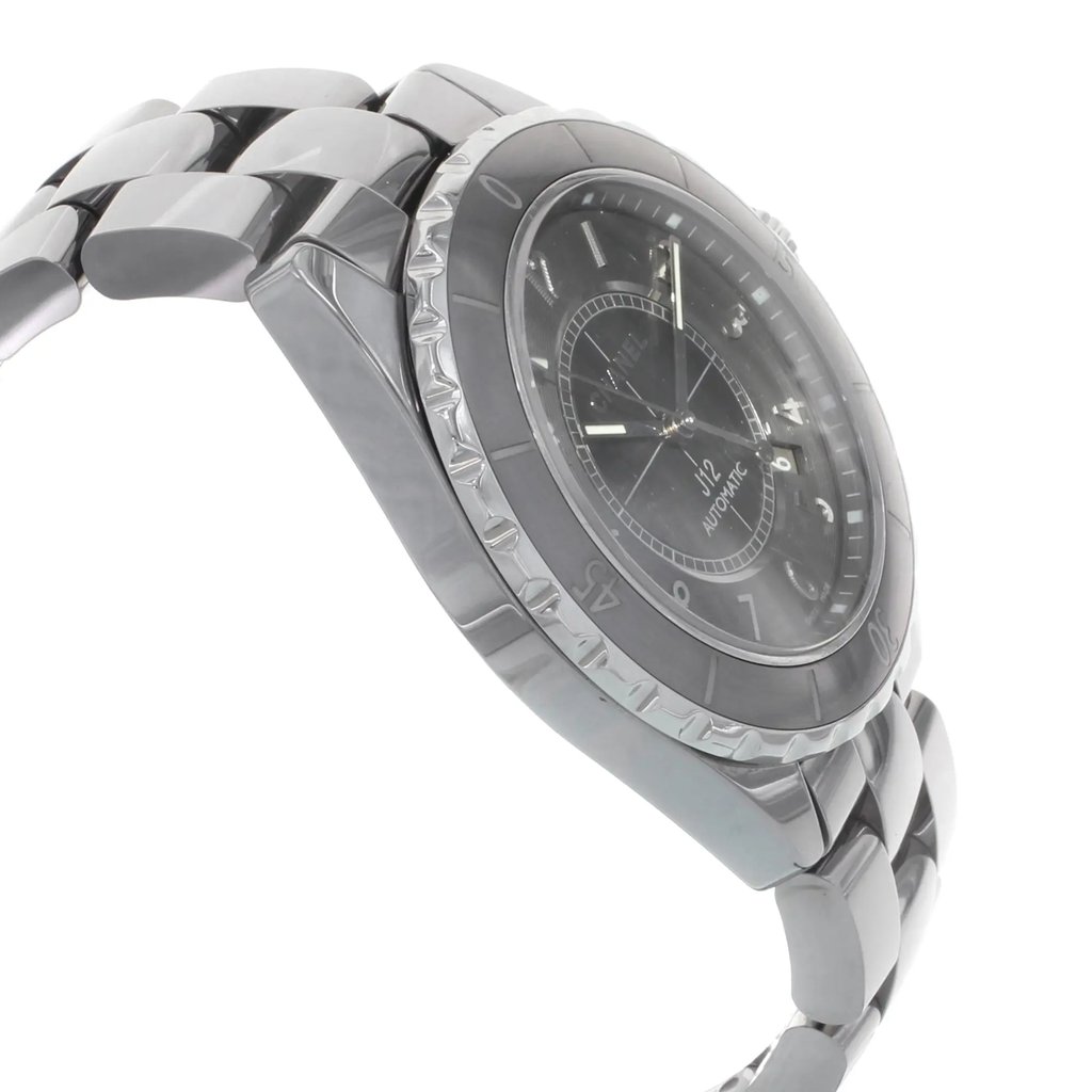 An image of a pre-owned wristwatch captured from a side profile view, opposite the crown. The watch features a polished metal bracelet and a dark round dial with visible hour markers. The angle highlights the thickness of the watch case and the intricately designed bezel, creating a sleek, reflective appearance. The photograph is taken at a close distance, emphasizing the watch's detailed craftsmanship.