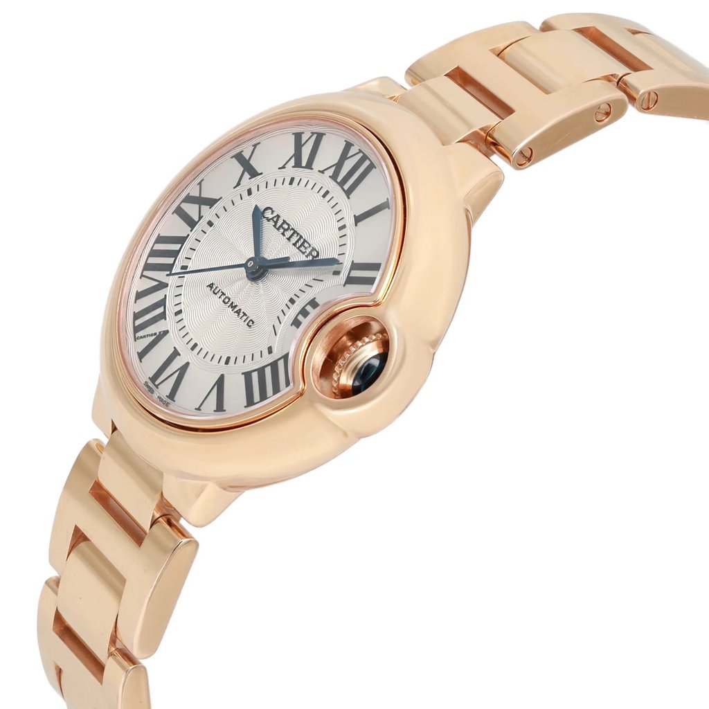An image of a pre-owned wristwatch shown from a side profile view, highlighting the crown. The timepiece has a metallic bracelet and a round watch face with Roman numerals, positioned at a slight angle to emphasize the design. The distance is close enough to showcase the details of the watch face and the crown.