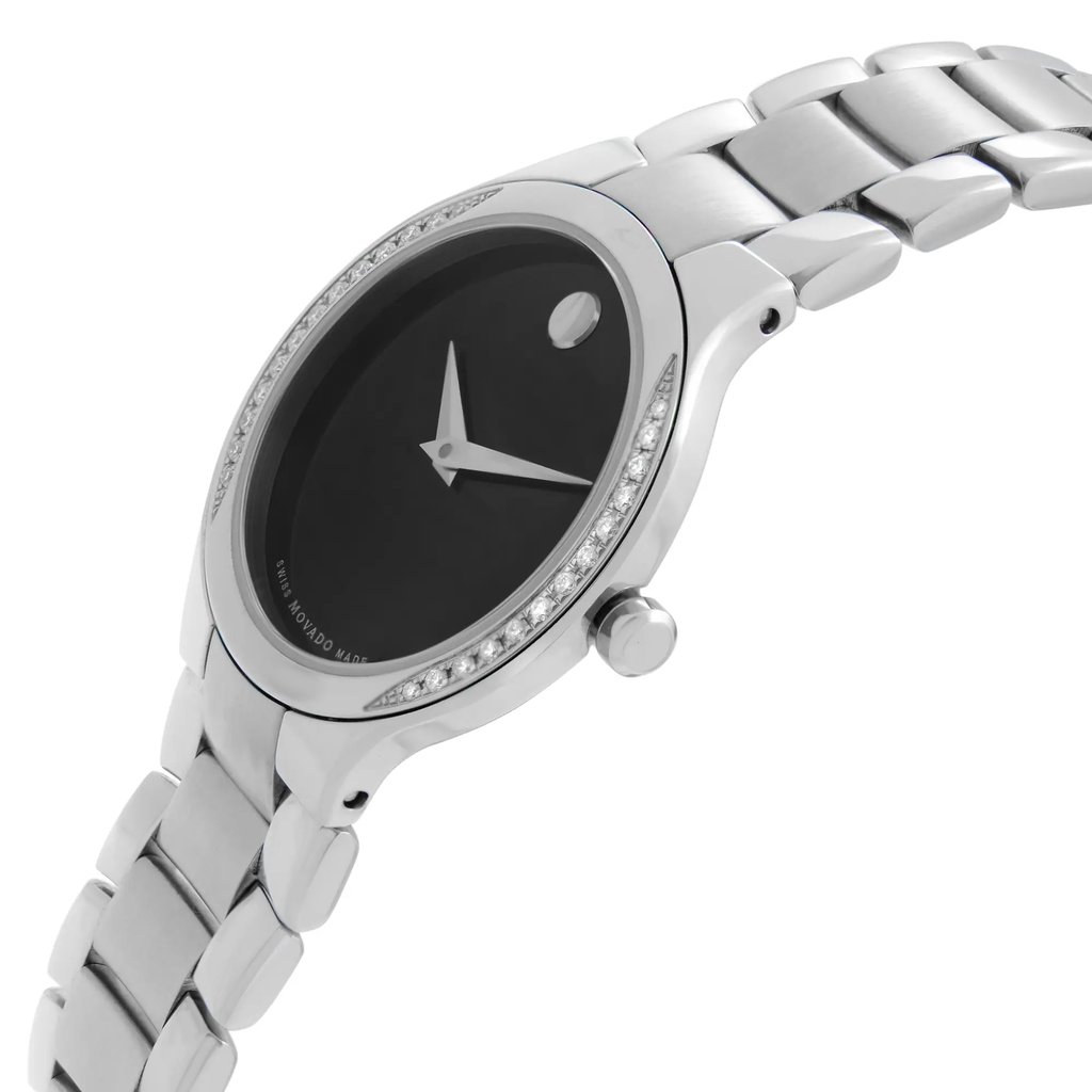 An image of a women's Movado wristwatch in an unworn condition, presented in a side profile view with the crown visible. The wristwatch features a round black dial, a stainless steel case and band, and a steel bezel adorned with diamonds suggesting a dress/formal style. The watch is positioned at a slight angle, with the dial facing slightly to the right and the band extending to the left, occupying the lower portion of the frame, showcasing its sleek design and fine craftsmanship.