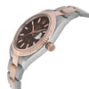 An image of a pre-owned Rolex wristwatch for men, presented in a side profile view with the crown visible. The watch features a round shape with a chocolate-colored dial and a rose gold bezel. It has luminous hands and a date indicator. The band is made of rose gold and stainless steel, while the case material is stainless steel. The watch is positioned at an angle that prominently displays the side of the case and the crown, with the watch face slightly tilted away from the viewer. The photo is taken from a close distance, emphasizing the luxurious style of the watch. Minor signs of wear or scratches are visible, indicative of its pre-owned condition.