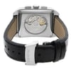 An image of a pre-owned wristwatch shown from the back view, highlighting its intricate mechanical movement through a transparent case back. The watch is positioned upright with its clasp closed, displaying a black leather strap. The image is taken from a close distance, focusing on the detailed workings and the brand name engraved on the clasp.