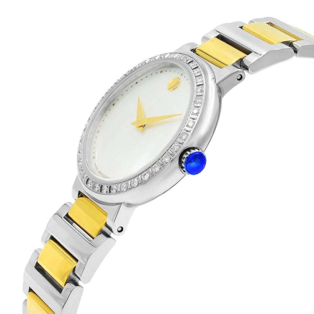 An image of a pre-owned wristwatch shown from a side profile view, highlighting the crown. The watch features a silver and gold two-tone bracelet and a bezel adorned with small stones. The face of the watch is white with gold hour and minute hands. The blue crown stands out prominently on the side. The angle and distance capture the sleek design and luxurious details.