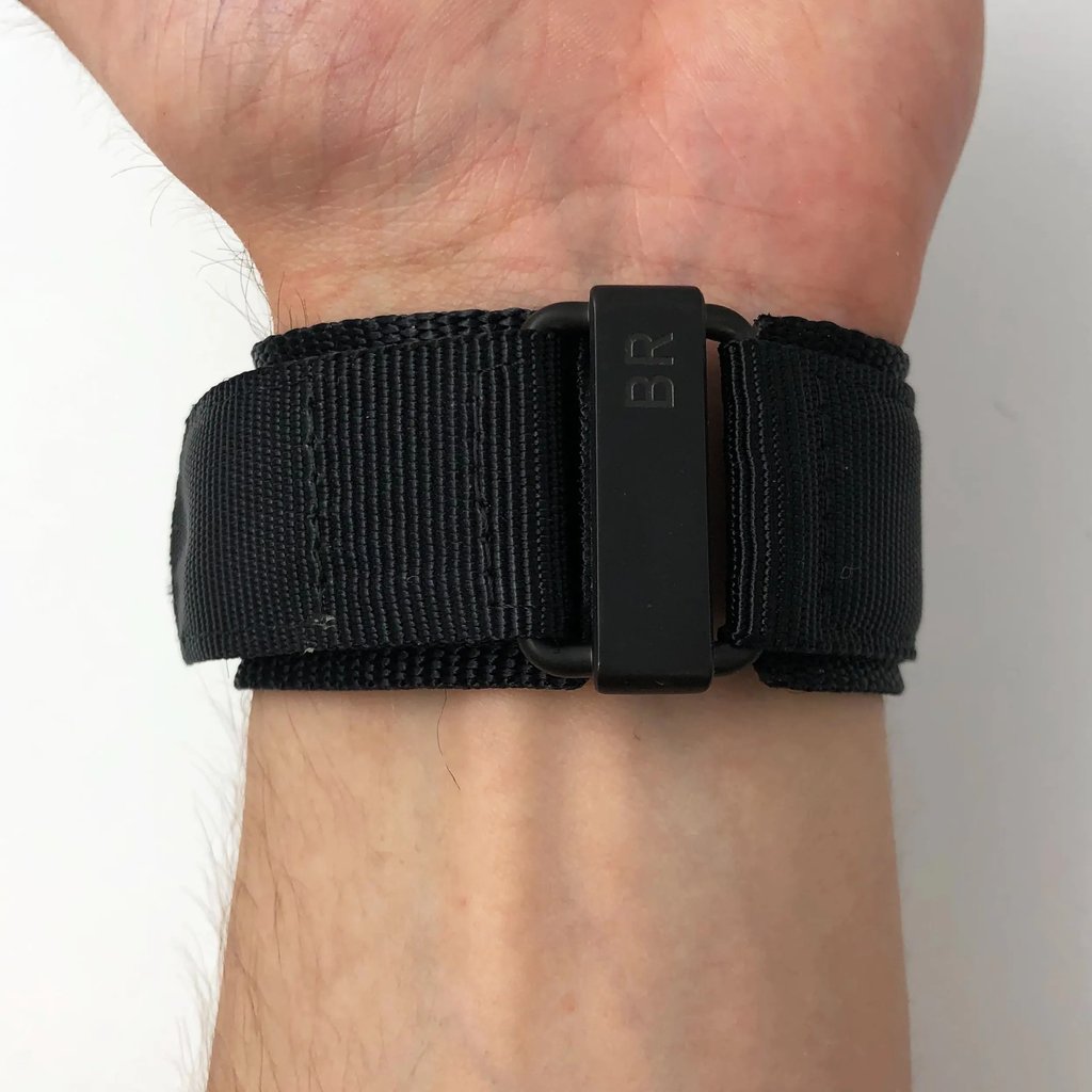 An image of a Bell & Ross men's wristwatch with a fabric/canvas band, shown from the back view on a wrist. focusing instead on the black buckle closure marked with "BR". with the band wrapped snugly around the wrist and the buckle centered in the frame shot from a direct, close-up angle.
