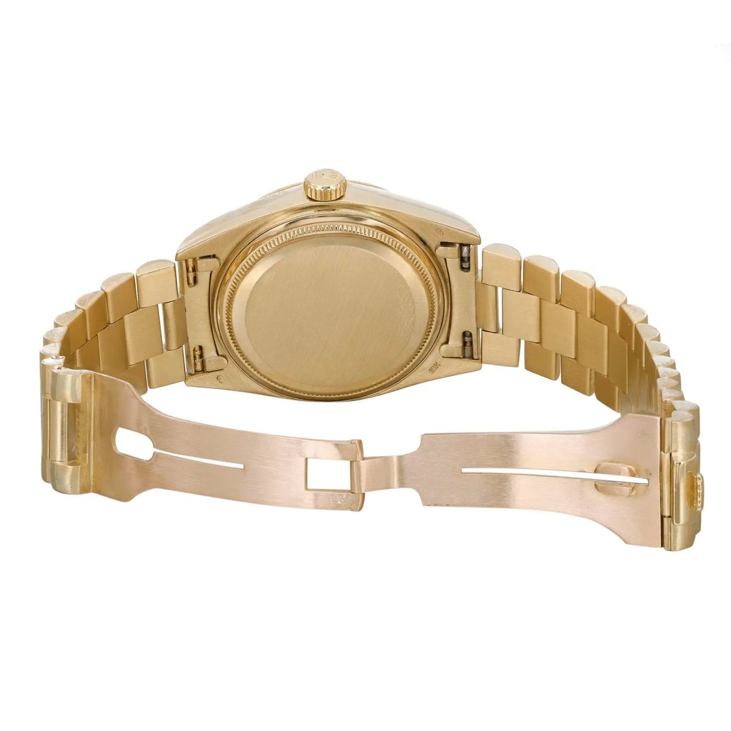 An image of a pre-owned Rolex men's wristwatch, showcasing the back view with an open clasp. The watch has a screwback caseback made of yellow gold, visible at the center of the frame, with a round shape. The yellow gold band material is also evident, with a fold-over clasp open on the right-hand side. The watch is positioned horizontally across the image with the top of the watch facing left and the clasp extended to the right, providing a clear view of the watch's design and condition from a rear perspective. The image is taken from a close distance, allowing for detailed inspection of the watch's features.  There may be light scratches on the case and bracelet Due to age