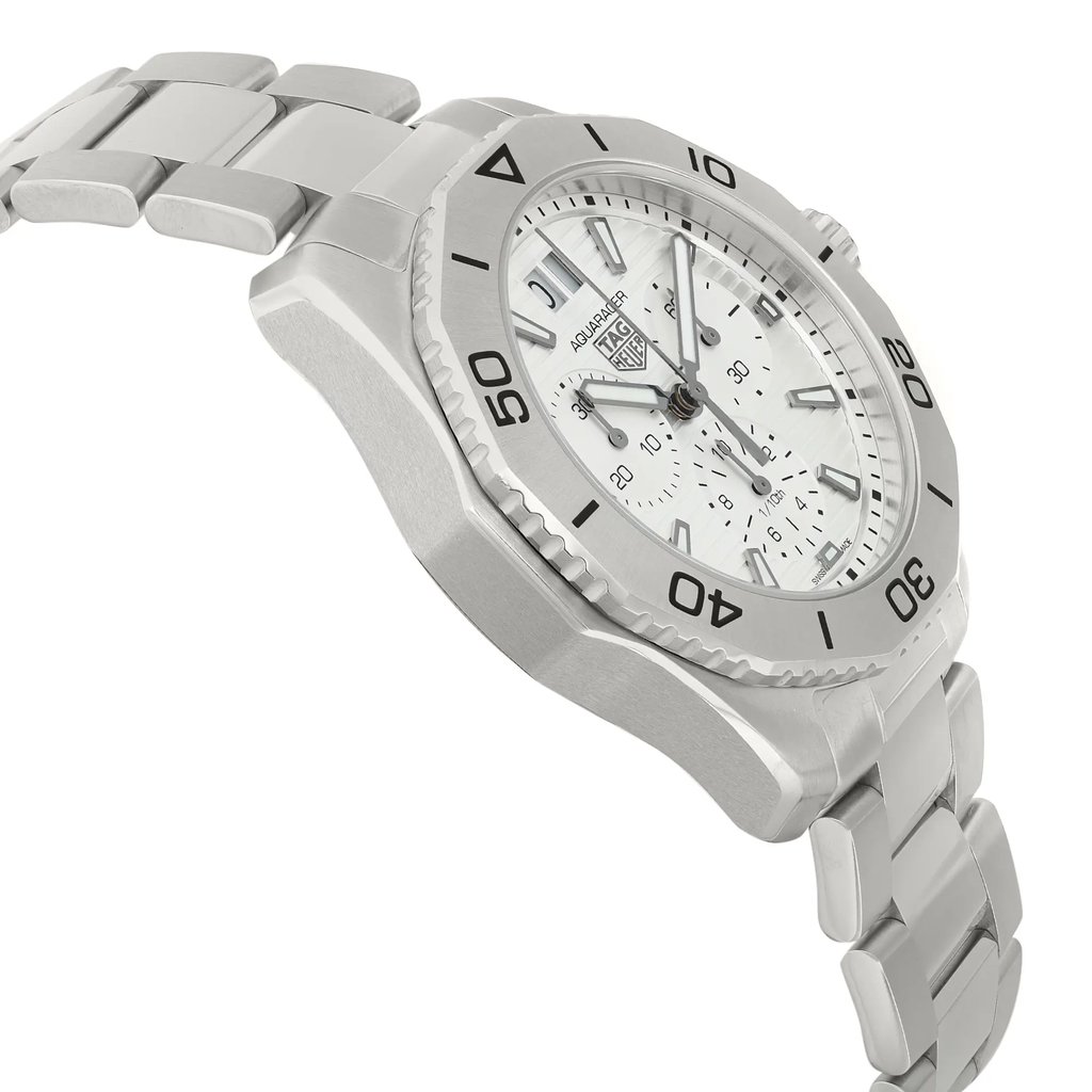 An image of an unworn TAG Heuer men's wristwatch in a side profile view opposite of the crown, showing a stainless steel band and case with a round shape. The dial is silver with a gray bezel, and the watch features a chronograph, date indicator, and small seconds subdial. The watch is positioned diagonally across the frame with the watch face and dial visible, and the band extending into the background, suggesting depth. The angle provides a clear view of the watch's side and the intricate design details on the face.