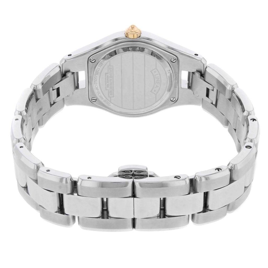 An image of a pre-owned wristwatch, viewed from the back at a close angle. The focus is on the clasp, which is centrally positioned in the foreground. The metal band is prominently displayed, showing its links and polished finish. The watch case back is visible in the background, slightly elevated, providing a full view of the intricate details on the clasp.