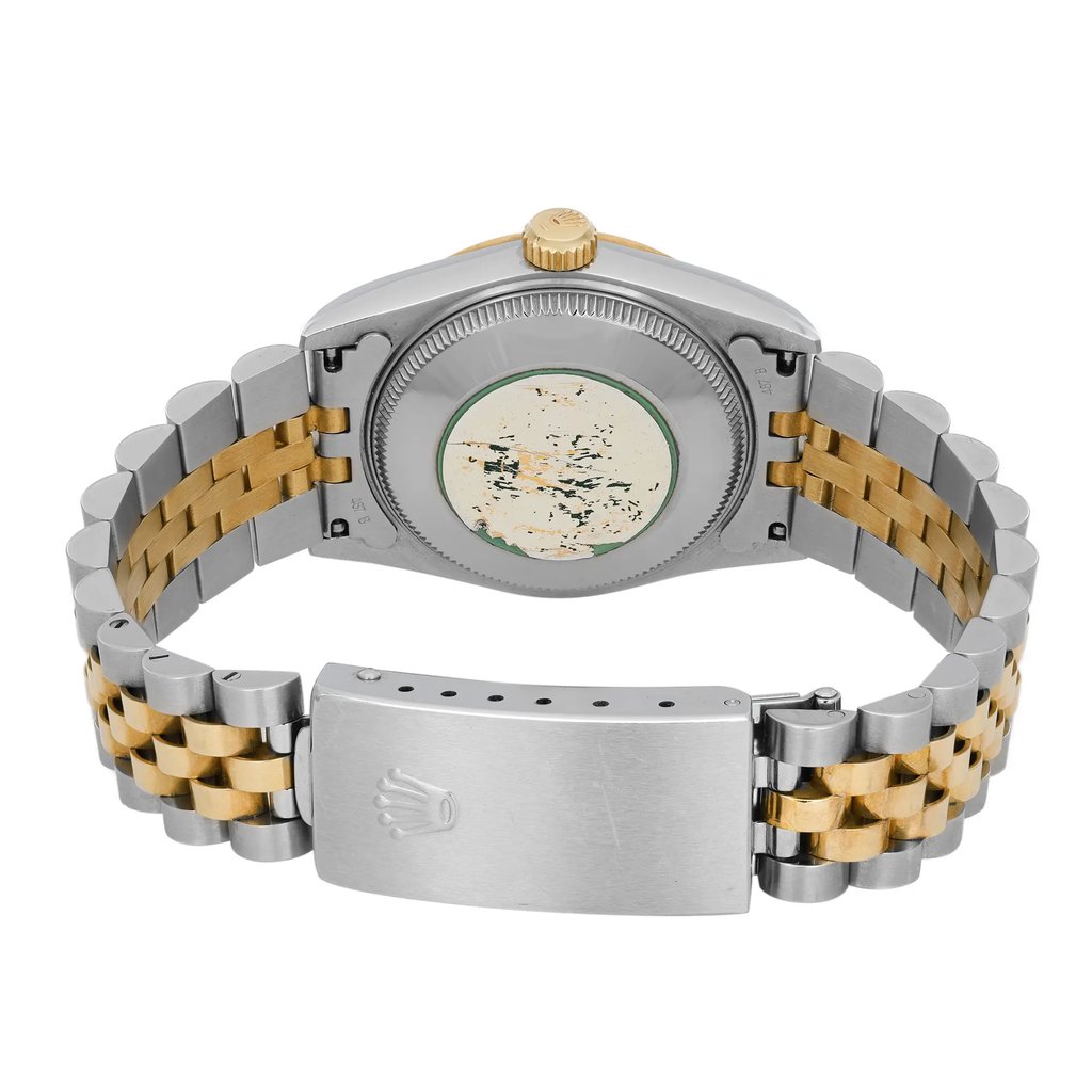 An image of a pre-owned wristwatch viewed from the back, showing a close-up of the clasp. The watch features a two-tone metal bracelet in silver and gold. The case back is visible, along with a worn sticker or engraving. The clasp is prominently displayed at the bottom of the image, slightly angled, with a crown emblem etched on it. The photograph is taken from a close distance, capturing the details of the watch's materials and design.