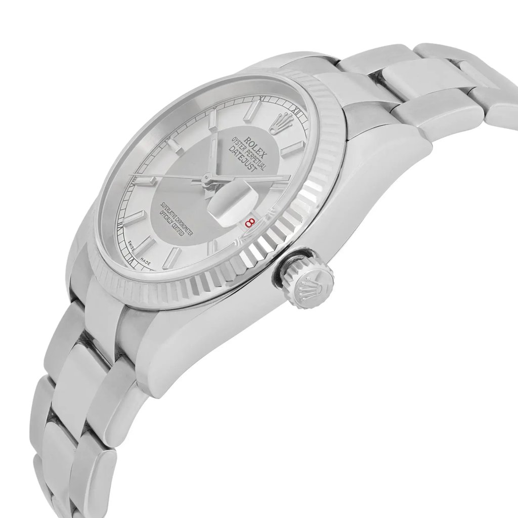 An image of a pre-owned men's Rolex wristwatch, positioned at a slight angle from the right side, showcasing the crown and part of the bracelet. The watch features a tuxedo silver dial with a date indicator and luminous hands, and it is captured from a close distance, highlighting the intricate details of the bezel and face.