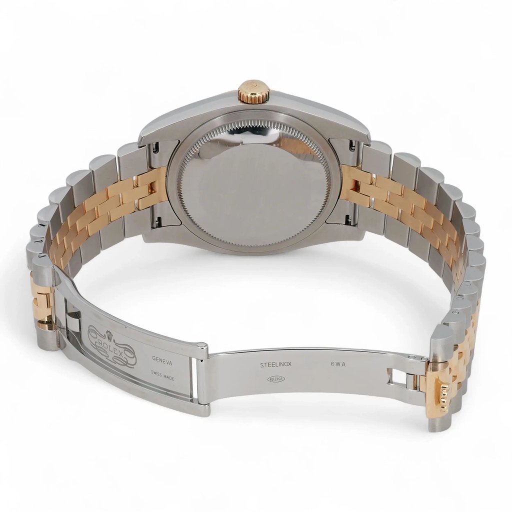 An image of a pre-owned Rolex wristwatch, viewed from the back at a slight angle. The watch is positioned centrally, showcasing its two-tone metal bracelet and closed clasp. The focus is on the back of the case, highlighting the crown at the top. The image is taken at a close distance, emphasizing the details of the bracelet links and clasp engraving.