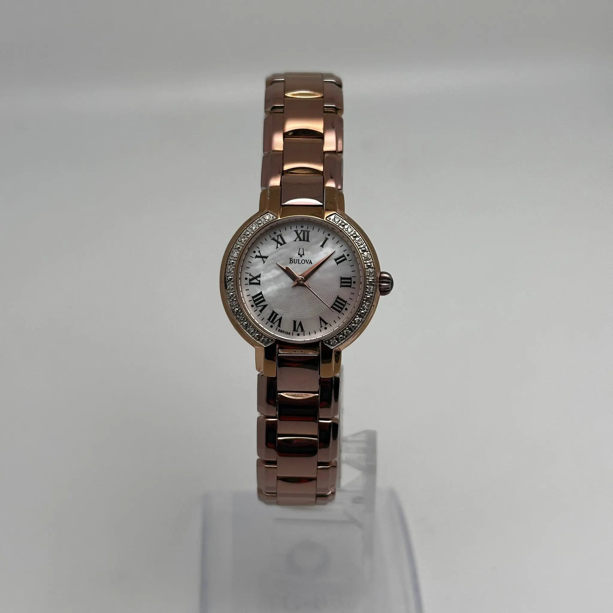An image of a Wristwatch by Bulova . This Pre Owned item is designed for Women, featuring a Casual style. It has a Quartz movement and an Analog display with a White dial color. The indices include 12-Hour Dial,Roman Numerals. The band is made of Rose Gold Plated,Stainless Steel and the case is made of Rose Gold Plated,Stainless Steel. The watch has a Round shape with a case size of 27 mm and a case thickness of 7 mm.