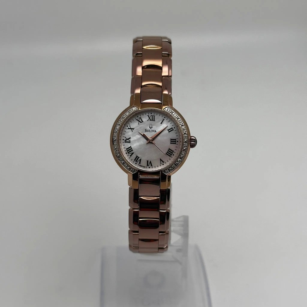 An image of a Wristwatch by Bulova . This Pre Owned item is designed for Women, featuring a Casual style. It has a Quartz movement and an Analog display with a White dial color. The indices include 12-Hour Dial,Roman Numerals. The band is made of Rose Gold Plated,Stainless Steel and the case is made of Rose Gold Plated,Stainless Steel. The watch has a Round shape with a case size of 27 mm and a case thickness of 7 mm.