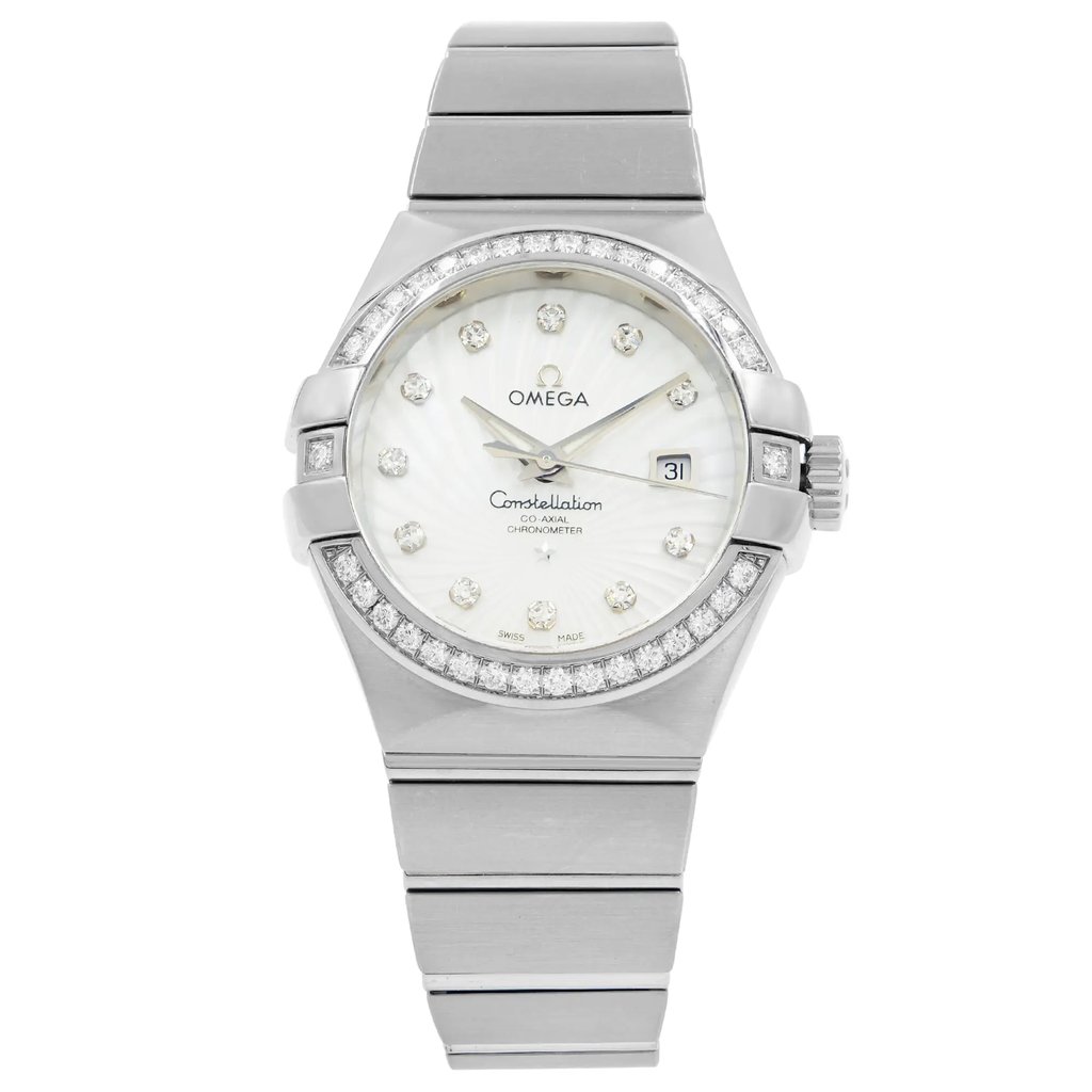 An image of a women's OMEGA Constellation wristwatch, displayed front-facing and centered at eye level. The watch features a white gold band and a round dial with diamond hour markers. The bezel is adorned with additional diamonds, and the date is visible at the 3 o'clock position. The watch is a display model, shown at a close-up angle to highlight its details.