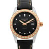 An image of a wristwatch displayed as a front close-up shot of the watch face. The watch features a black dial with gold hands and diamond hour markers. The bezel is adorned with diamonds and has a gold finish. The date is visible at the 3 o'clock position. The watch is in display model condition and has a black leather strap with stitching details.