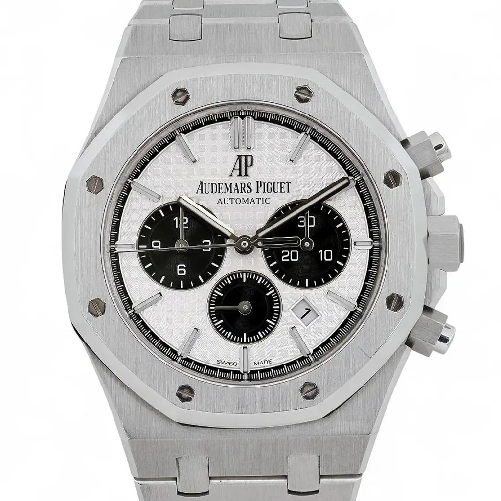 An image of a pre-owned Audemars Piguet men's wristwatch, viewed from a straight-on angle, showcasing the watch face prominently. The timepiece features a silver-toned, octagonal bezel and a stainless steel bracelet. The dial is white with three black subdials, and the brand name is clearly visible below the 12 o'clock position. The watch hands are luminous, providing enhanced visibility. The image is taken from a close distance, highlighting the intricate details and craftsmanship of the watch.