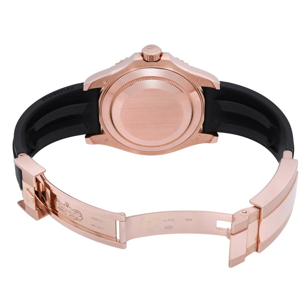 An image of a pre-owned men's Rolex wristwatch viewed from the back at a close distance. The watch is positioned horizontally, showcasing its rose gold case and clasp with an open black strap. The focus is on the back casing and band, highlighting the intricate details and engravings on the clasp.