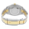 An image of a pre-owned wristwatch showing the back view with a closed clasp. The watch is positioned centrally, capturing the two-tone metal bracelet in silver and gold. The focus is on the clasp, which is engraved with a distinctive logo, and the case back, positioned in the upper part of the image. The angle is slightly elevated from behind, and the photograph is taken at a close distance, highlighting the details and finish of the materials.