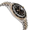 An image of a pre-owned wristwatch captured from the side profile view, opposite the crown, at a slight angle. The watch showcases a two-tone metal bracelet and a black dial with gold accents, including a numbered bezel. The angle highlights the watch's thickness and detailed craftsmanship.
