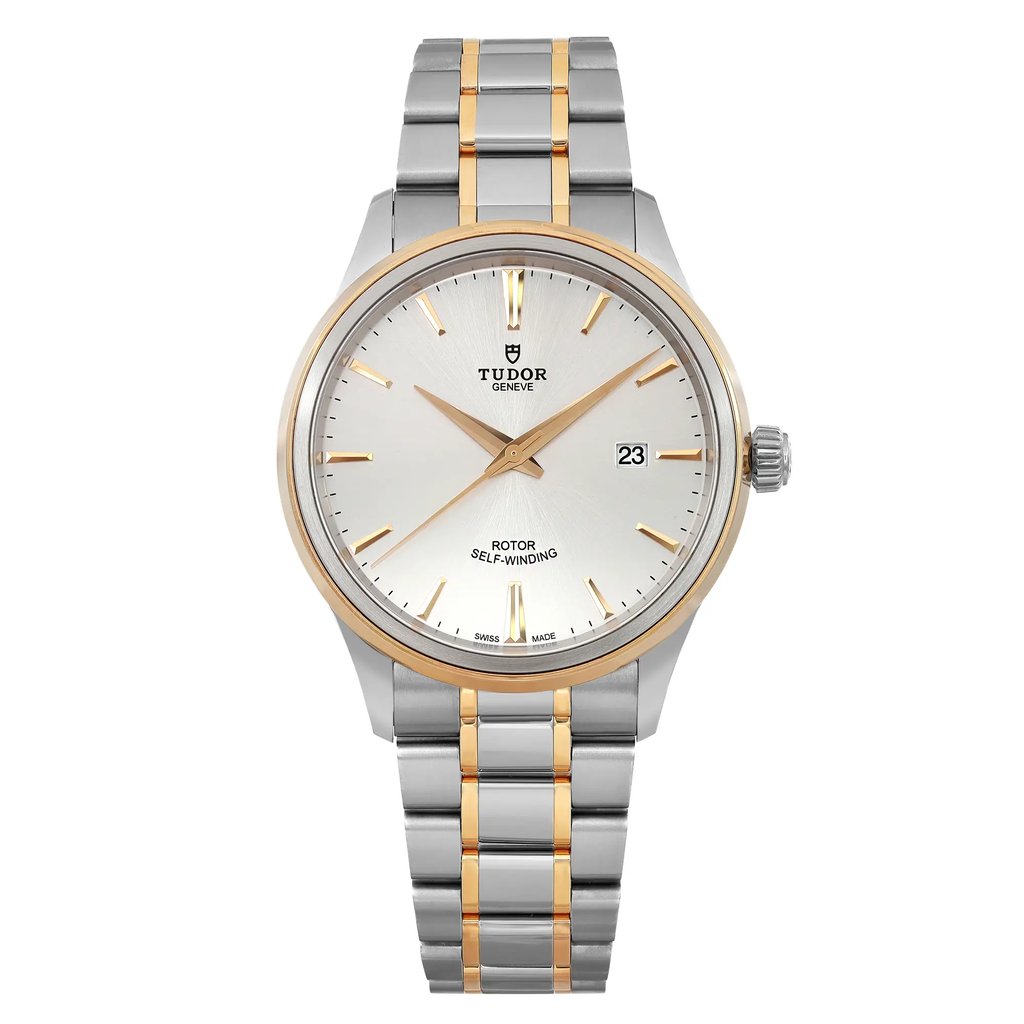An image of a men's TUDOR Style 41mm wristwatch in unworn condition, featuring a date indicator. The watch is positioned upright, displaying a close-up, frontal view. It has a silver dial with yellow gold hands and markers, and a two-tone metal bracelet with gold and steel links. The watch face is clear and detailed, highlighting the brand name and self-winding rotor feature.