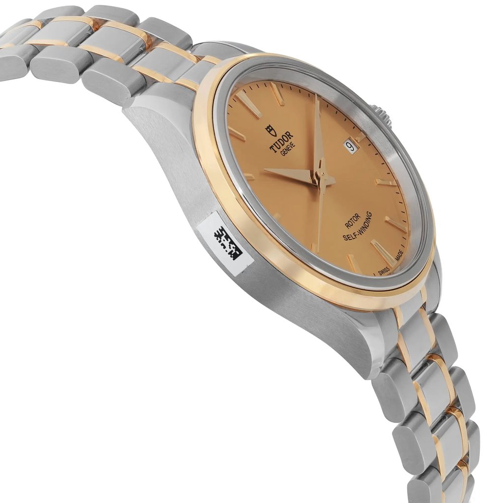 An image of a wristwatch in a side profile view, opposite of the crown, showcasing its unworn condition. The watch features a two-tone metallic bracelet and a dial with a smooth finish. The angle highlights the sleek design and craftsmanship of the watch, emphasizing its elegant curves and detailing from a close distance.