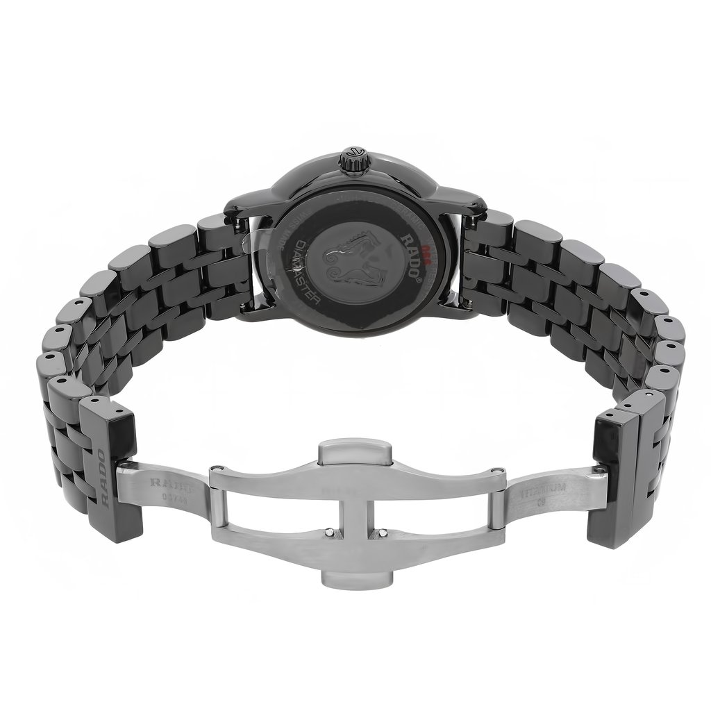 An image of a wristwatch showing the back view with an open clasp positioned centrally. The angle highlights the intricate links of the metal bracelet and the watch's back case. The image is taken from a close distance, allowing detailed observation of the design and craftsmanship. The condition is noted as new with defects.